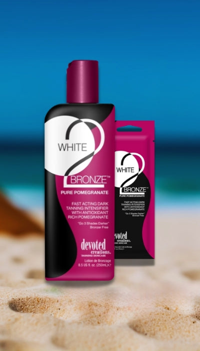 Two bottles of 'White Bronze' tanning product on a beach with blue water in the background.